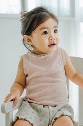 Baby girl sitting in Avauma baked peach sleeveless tank top and floral shorts – cozy summer outfit